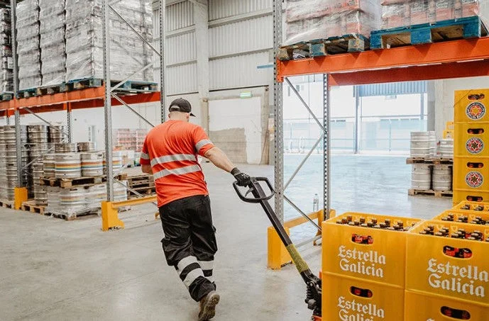 Trabajador arrastrando palet con cervezas Estrella Galicia